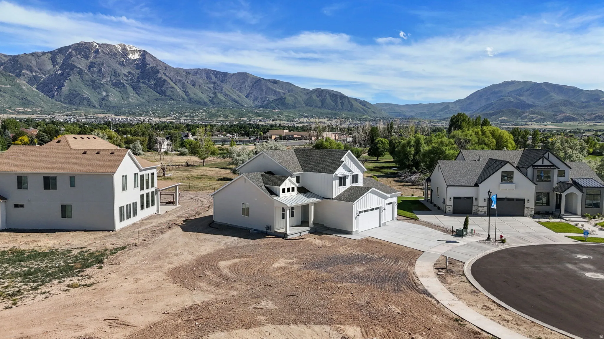 Newly constructed residence featuring a white facade, gabled roofline, and an attached three-car garage