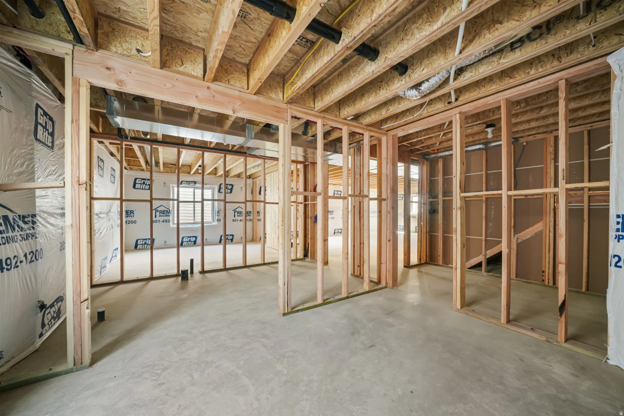 Unfinished basement with concrete flooring, exposed wood framing, and visible ceiling joists