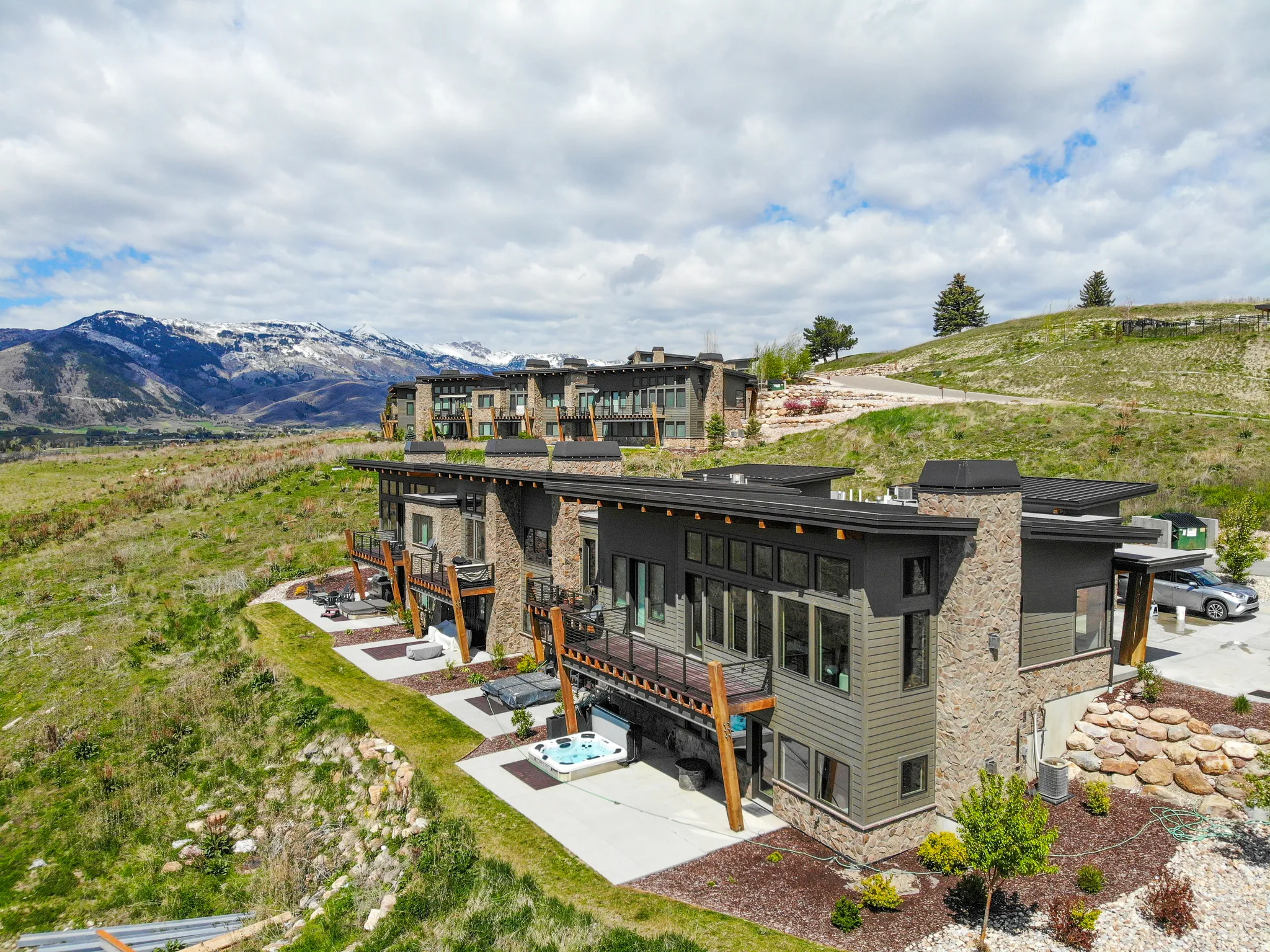 Rear view of house with stone siding, a mountain view, a patio, and a chimney