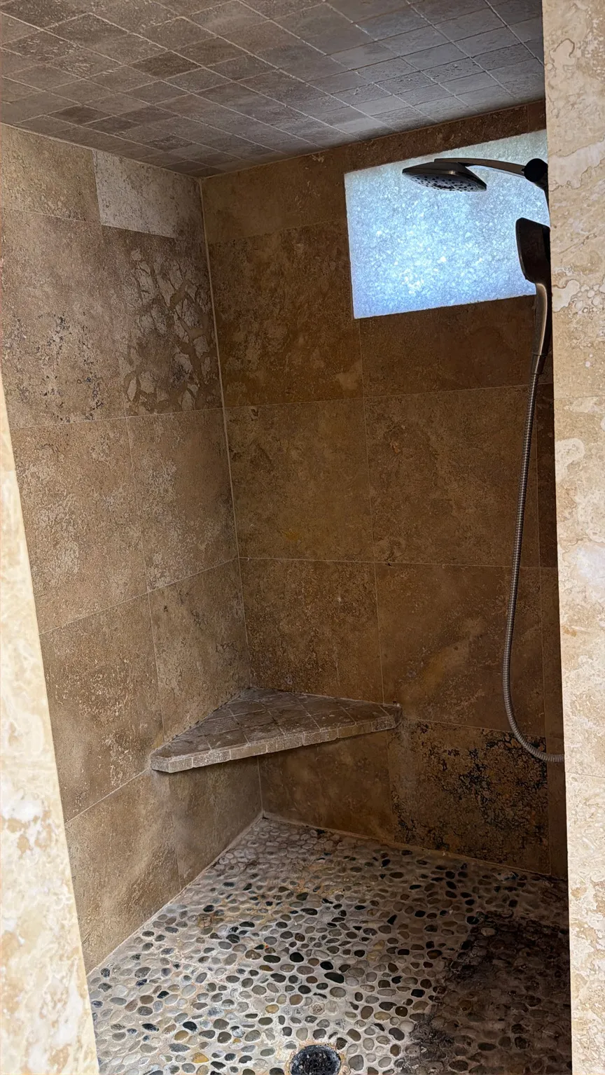 Bathroom featuring a tile shower and stone finish flooring