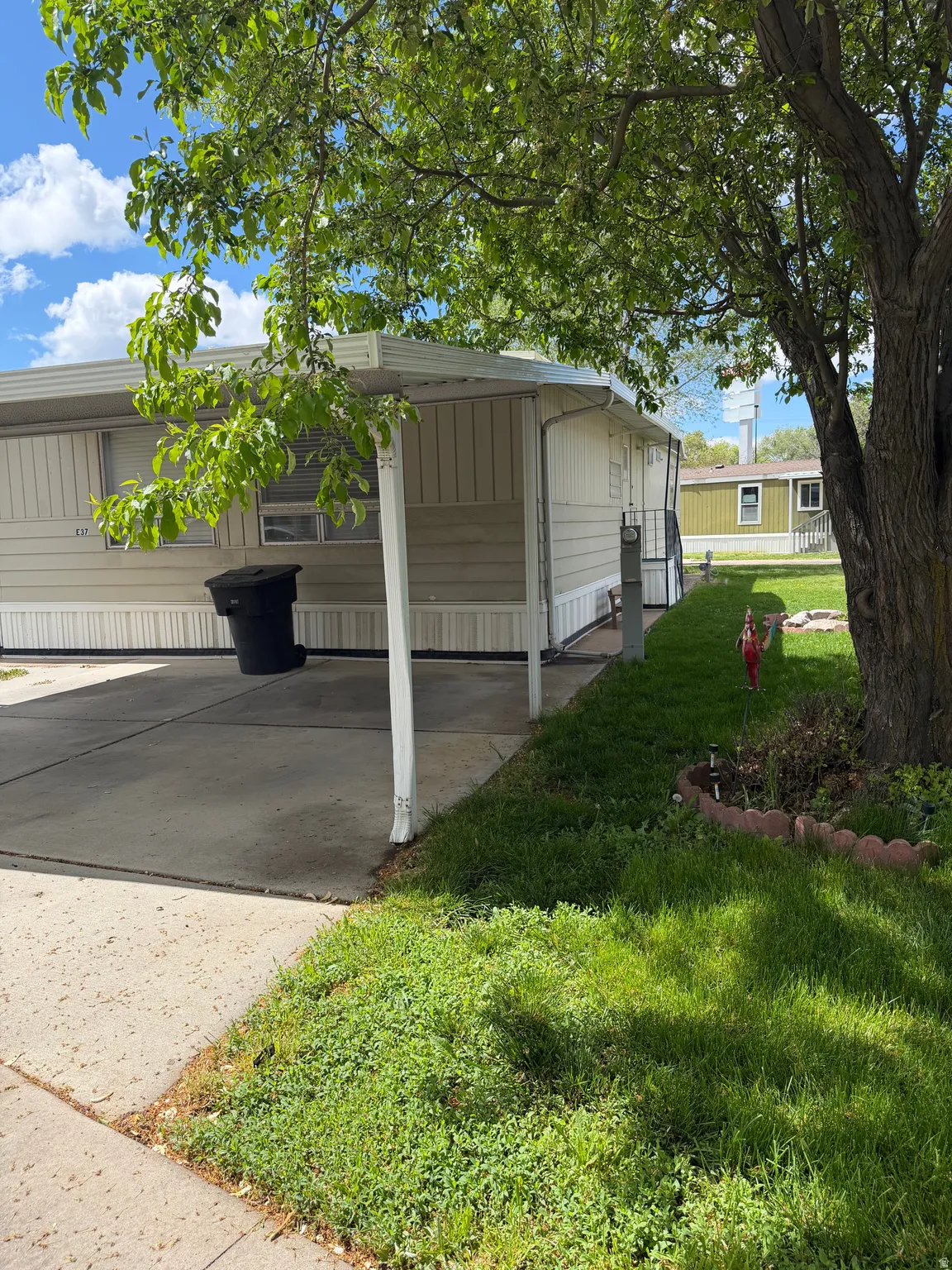 View of property exterior featuring a lawn, a carport, and driveway