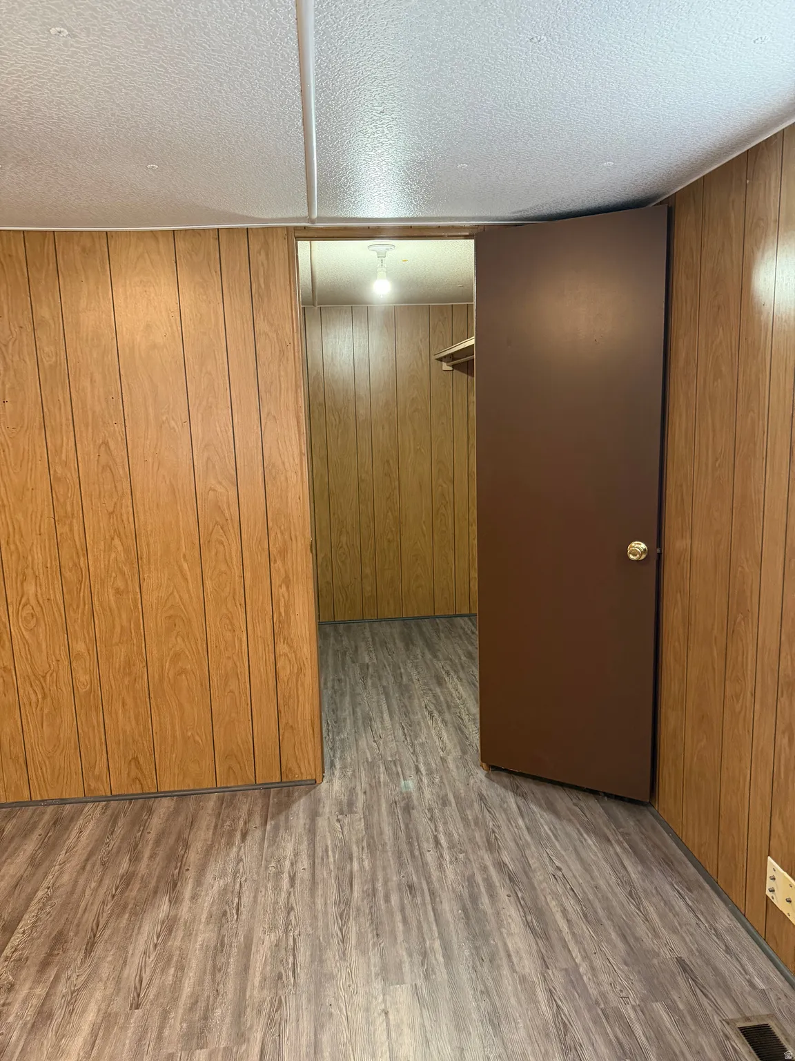 Master walk-in closet with a textured ceiling, wood finished floors, and wood walls