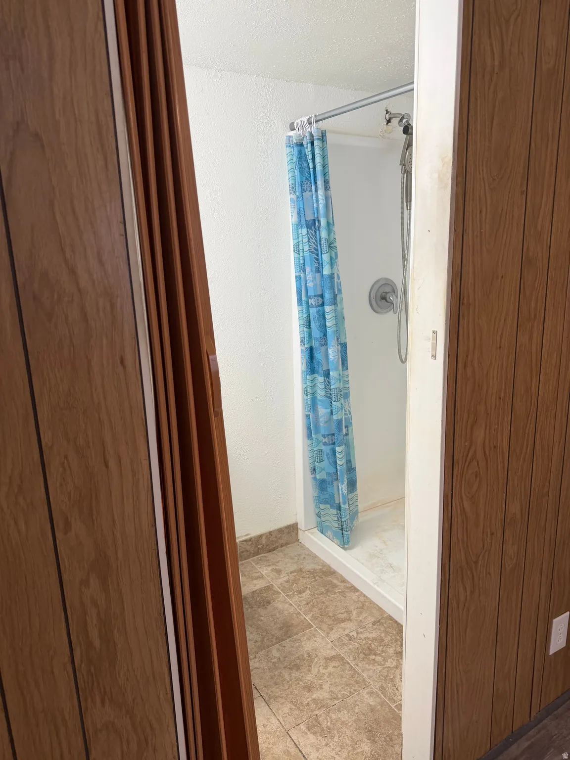 Full bath with a stall shower and a textured wall