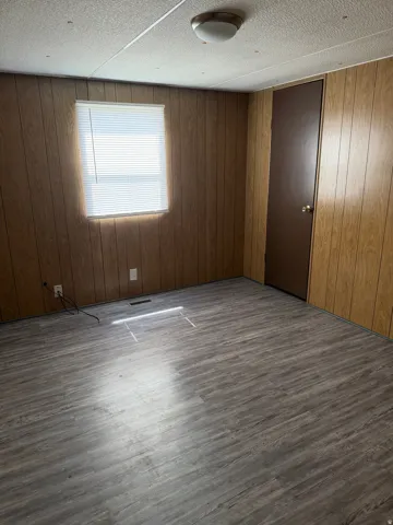 Master bedroom featuring wooden walls and dark wood finished floors w/bathroom