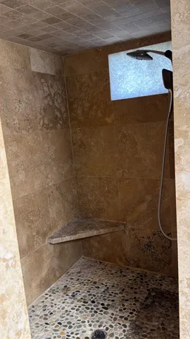 Bathroom featuring a tile shower and stone finish flooring