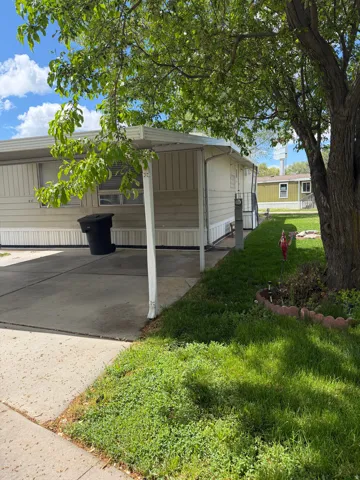 View of property exterior featuring a lawn, a carport, and driveway