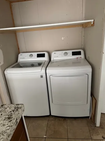 Laundry area with washer and dryer and dark tile patterned floors