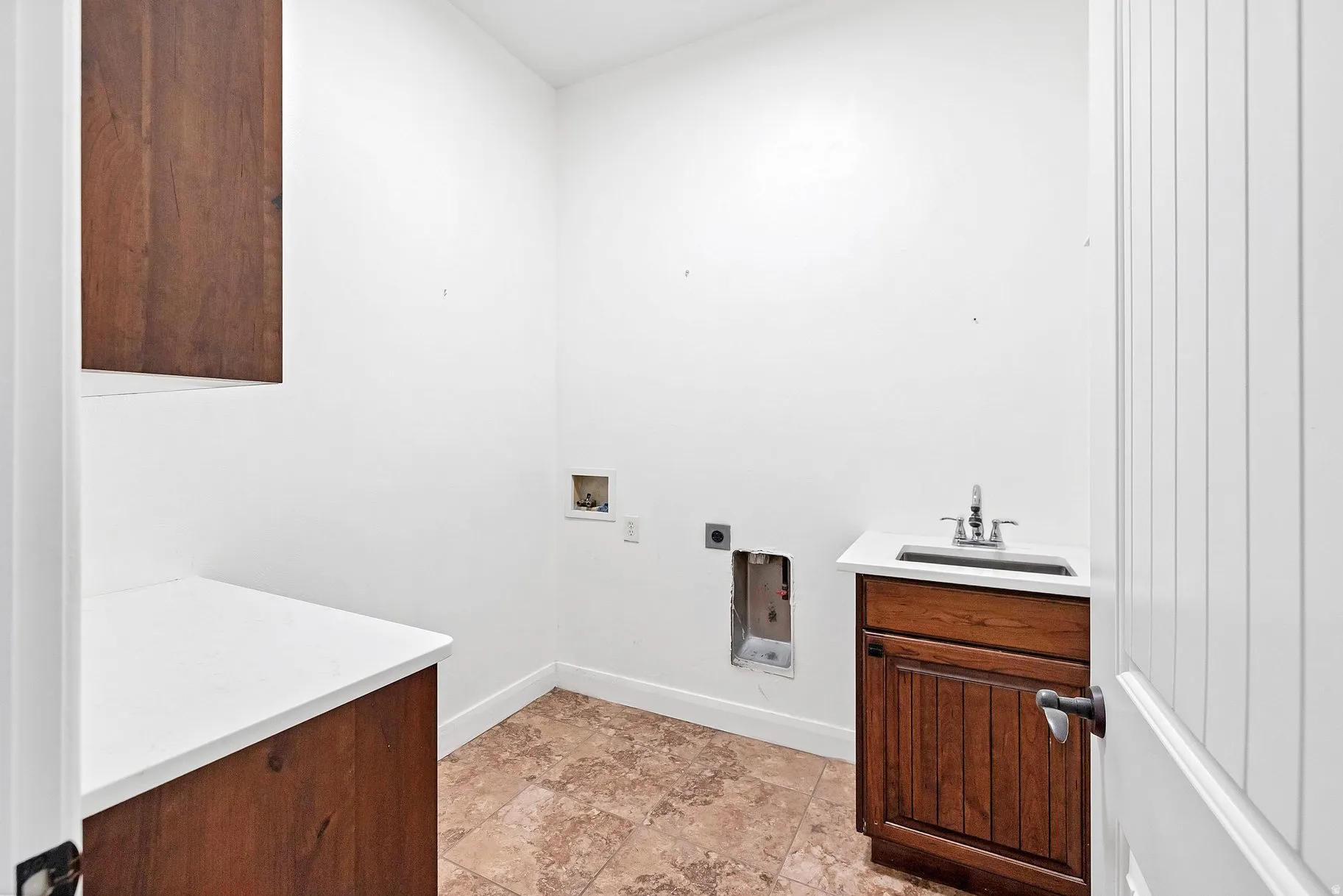Laundry area with washer hookup, cabinet space, electric dryer hookup, and stone finish floors