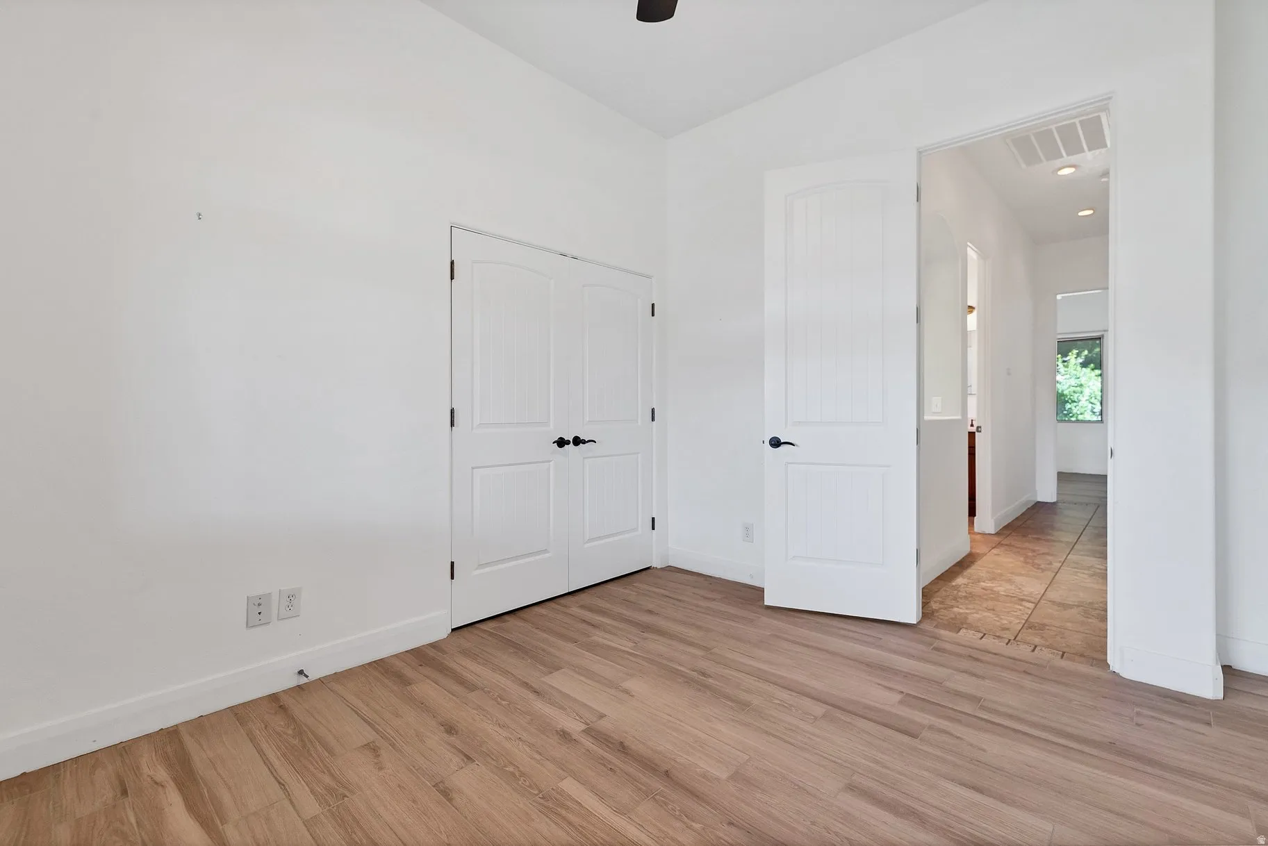Unfurnished bedroom featuring light wood finished floors, vaulted ceiling, a closet, and ceiling fan