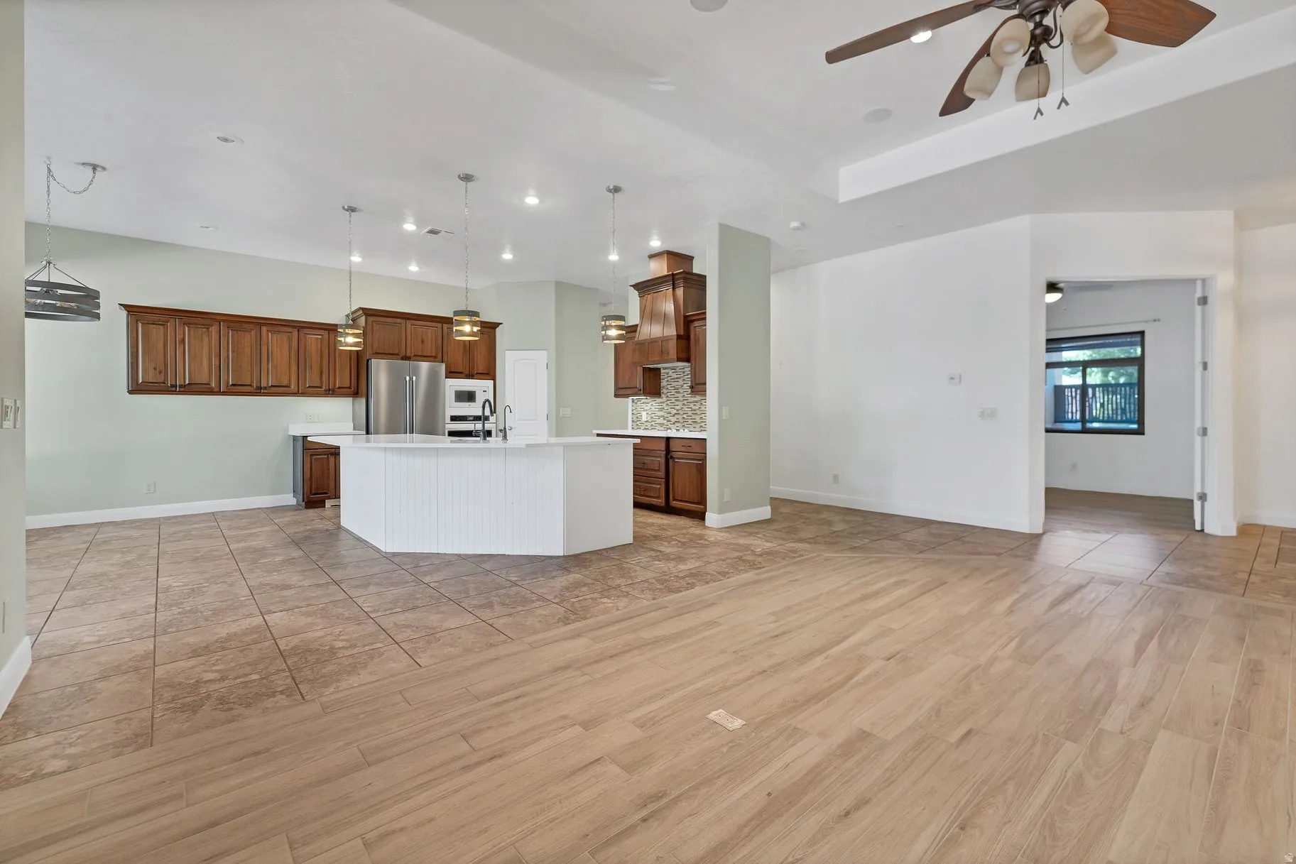 Kitchen featuring open floor plan, light countertops, a center island with sink, wood finish cabinetry, and light wood-style floors