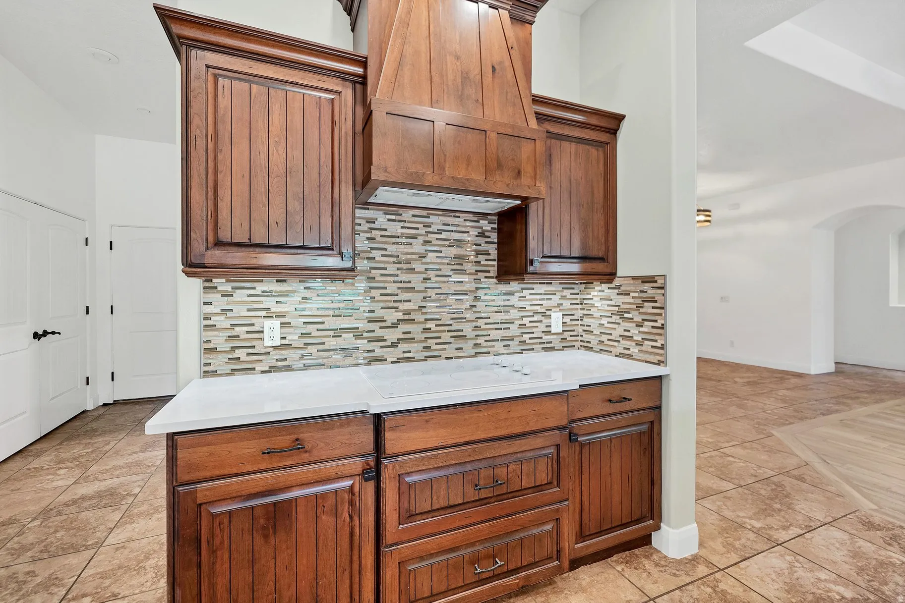 Kitchen featuring arched walkways, backsplash, and light tile patterned flooring