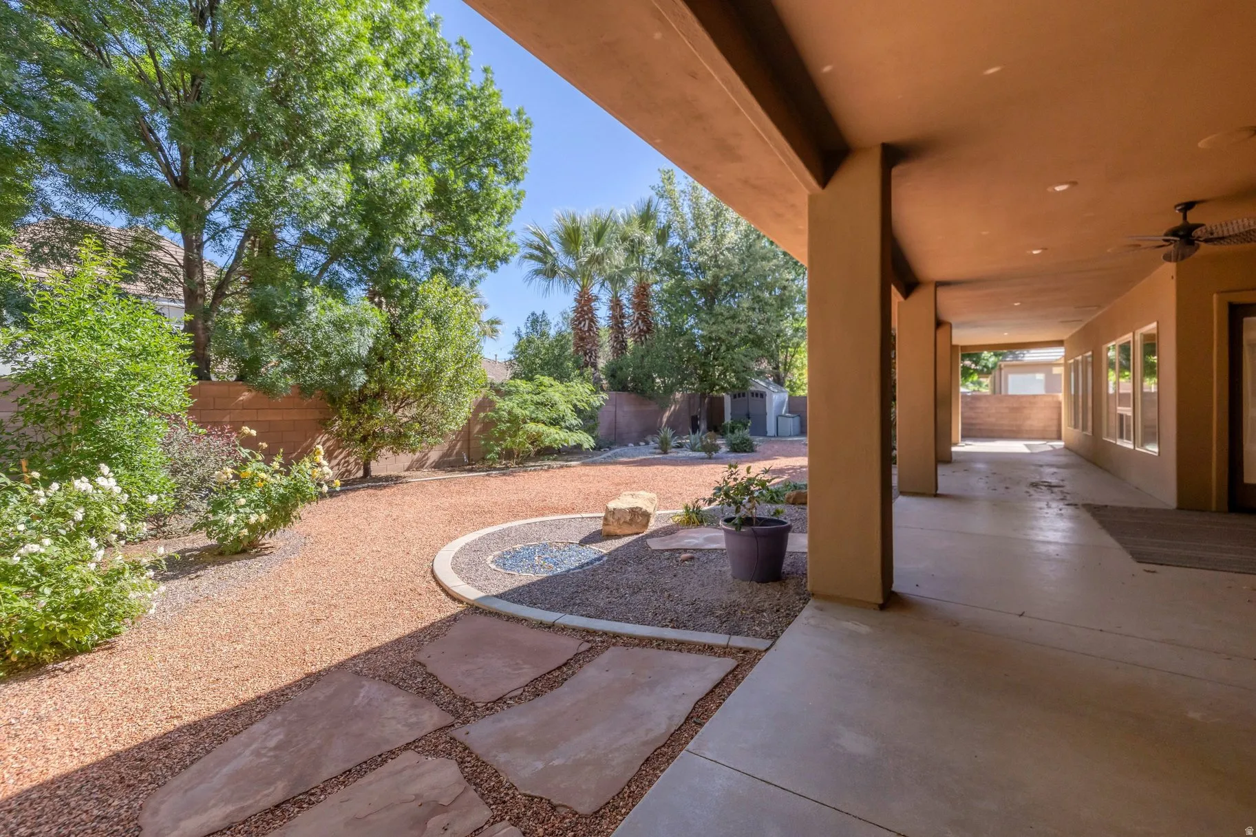 Fenced backyard with a ceiling fan and a storage unit