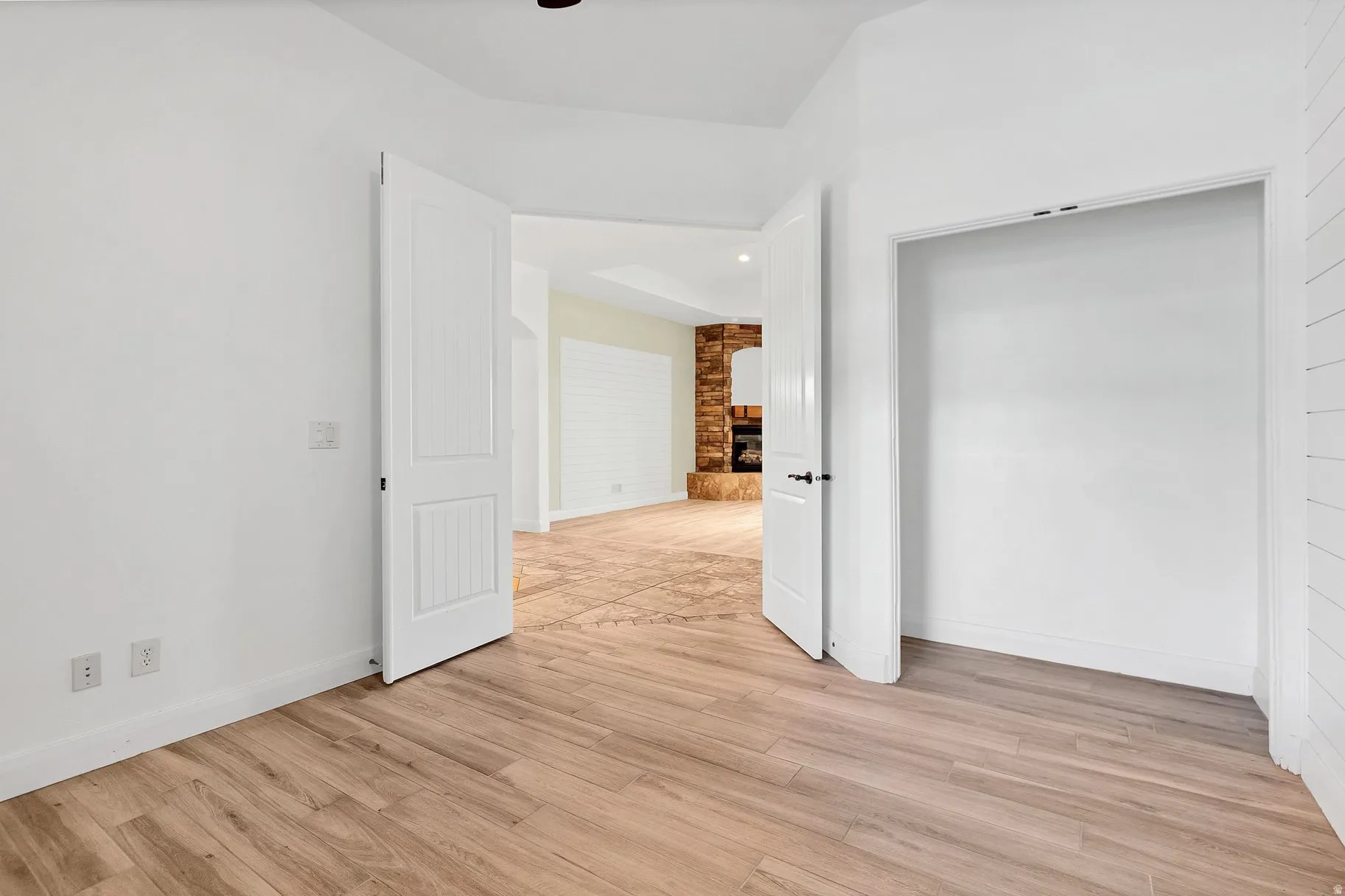 Unfurnished bedroom with light wood finished floors, a brick fireplace, and a ceiling fan