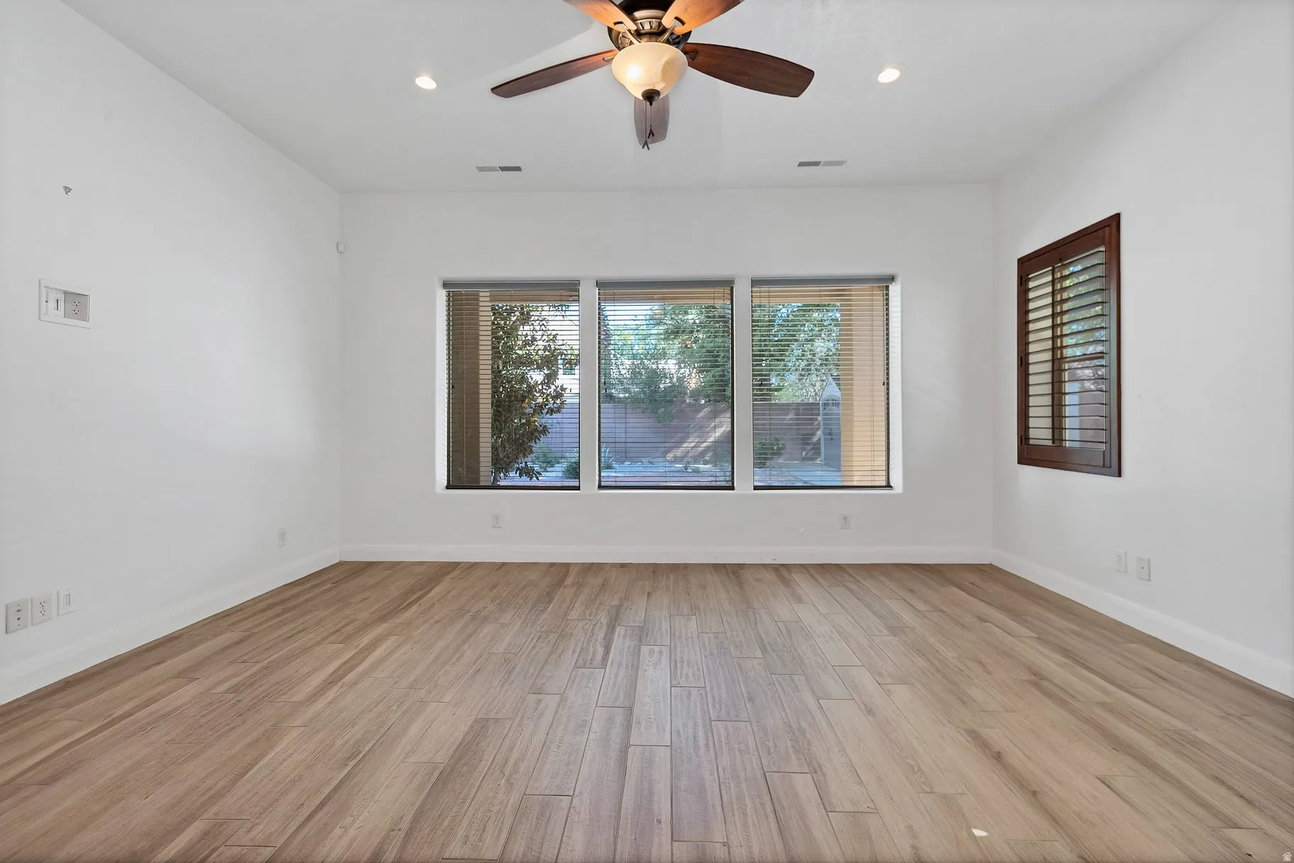 Empty room featuring ceiling fan, light wood finished floors, and recessed lighting