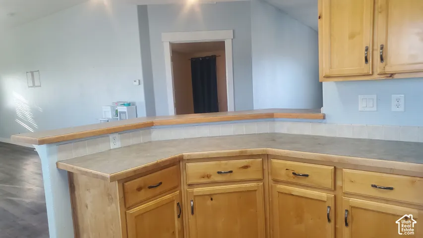 Corner kitchen cabinetry with wood-finish doors and dark hardware, complemented by a wraparound countertop and tile backsplash
