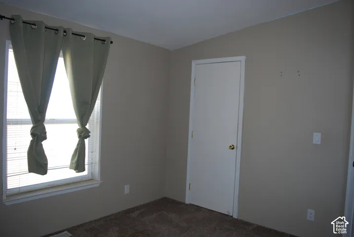 Neutral-toned room featuring a single window with blinds and a full-height interior door
