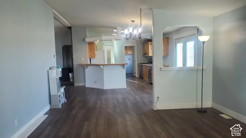 Wood-finish flooring throughout, light blue wall paint, kitchen with wood cabinetry, and a pass-through window to the adjacent space