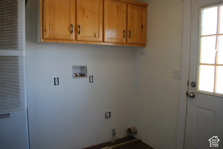 Laundry area featuring wood cabinetry with black hardware, washer/dryer hookups, and a panel door with window panes