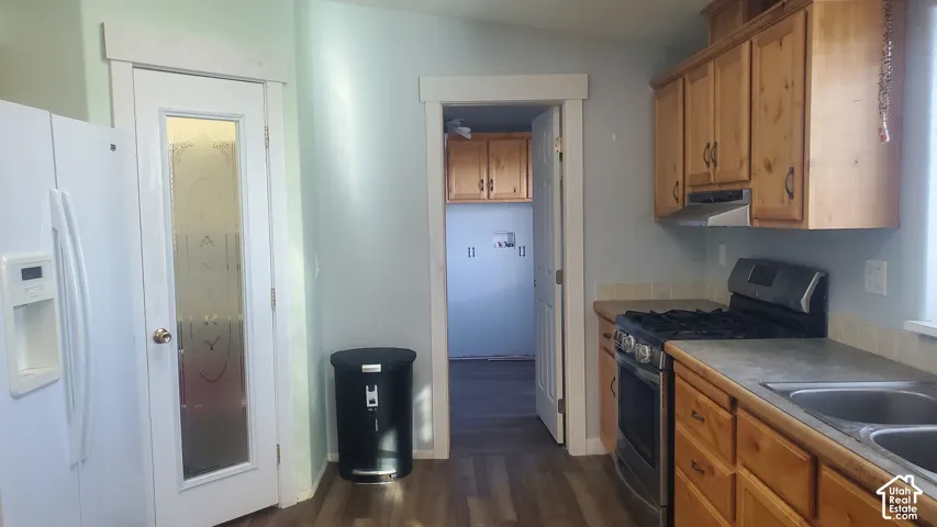 Wood-finish flooring, wood cabinetry, stainless steel range, and a double-basin stainless steel sink
