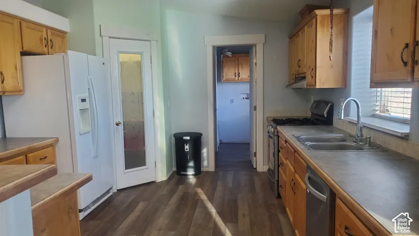 Kitchen featuring wood-finish flooring, natural wood cabinetry, a double basin stainless steel sink, and a gas range