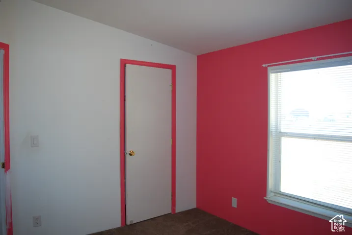 Room featuring a bright accent wall, neutral carpeting, and a window with blinds