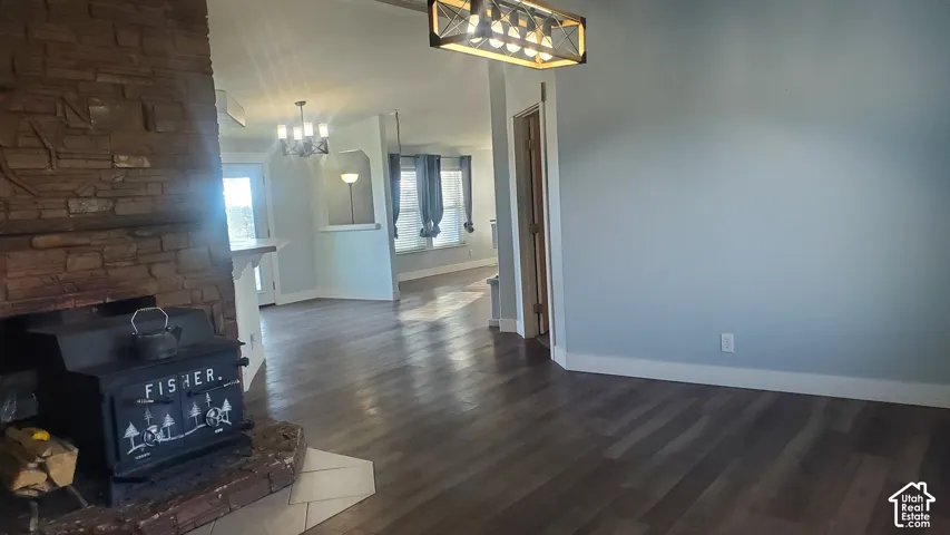 Wood-finish flooring throughout, stacked stone fireplace with stove insert, contemporary ceiling light fixture, and light blue wall color