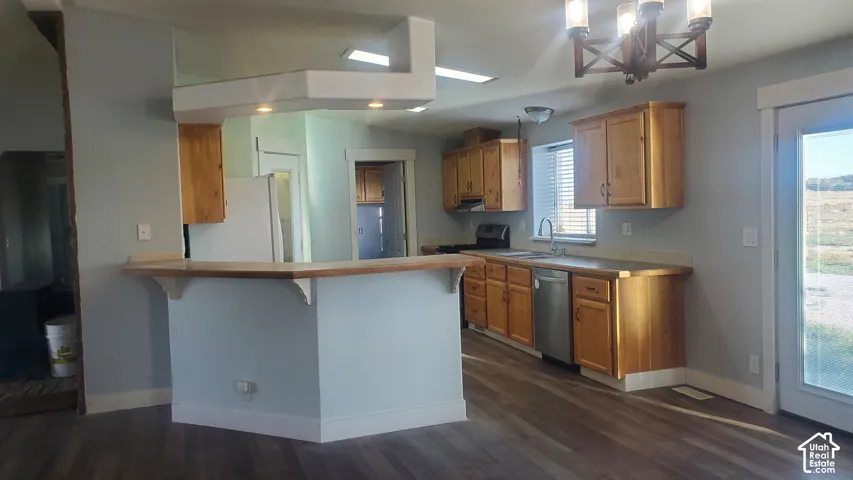 Wood-finish flooring, light wood cabinetry, a breakfast bar, and a stainless steel dishwasher