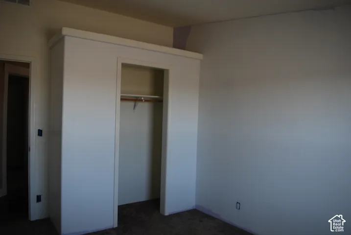 Built-in closet with a wooden rod and shelving, framed by white trim and a neutral wall color