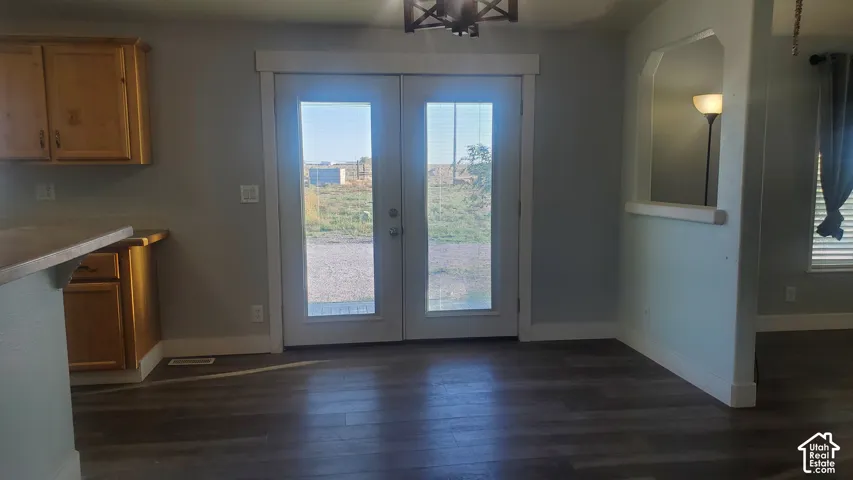 Glass-paned French doors, wood-finish flooring, light-toned walls, and wood cabinetry