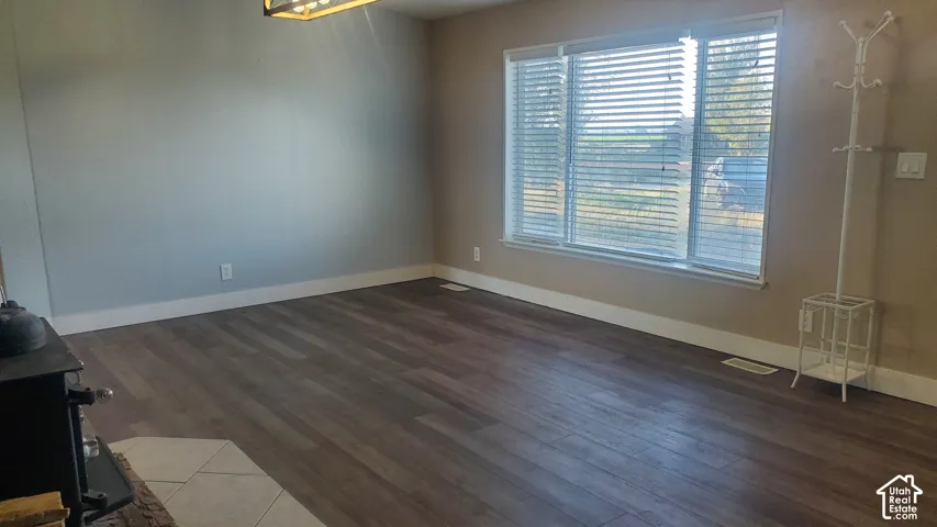 Wood-finish flooring, large window with horizontal blinds, and a built-in wood-burning stove