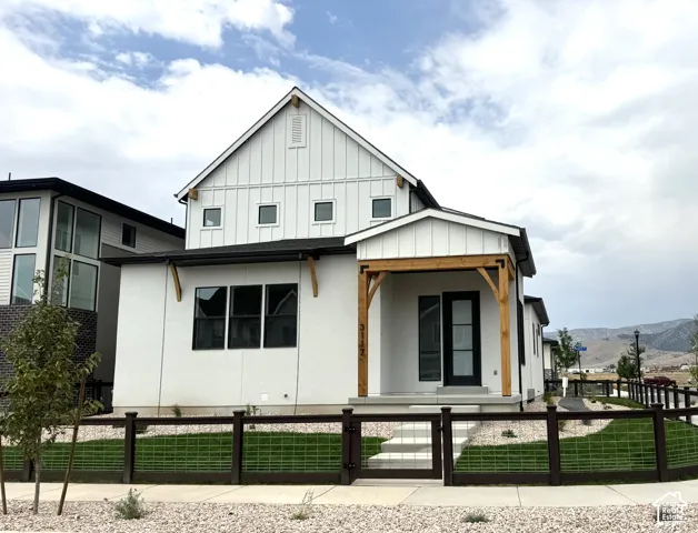 Modern farmhouse residence featuring a peaked gable roof with board-and-batten siding, black-framed multi-pane windows, and warm wood-tone architectural accents