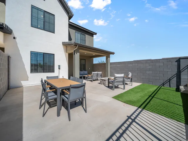 Expansive concrete patio with a covered outdoor area, artificial turf section, and a block perimeter wall