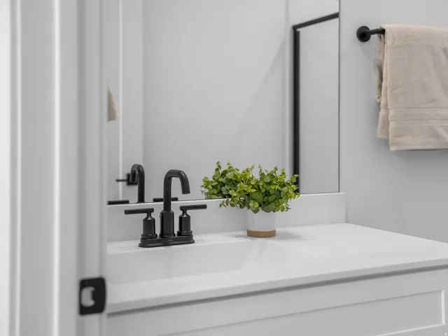 White vanity with a rectangular undermount sink, a solid surface countertop, and matte black fixtures