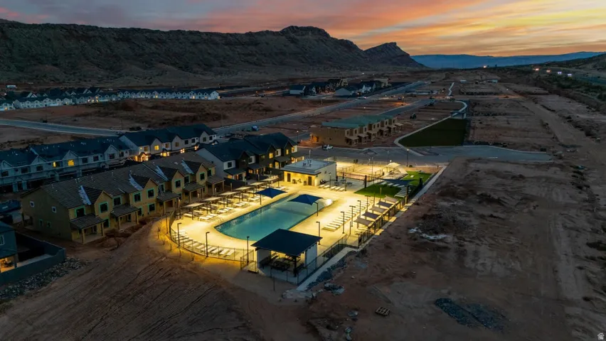 Community pool with surrounding lounge seating, shaded cabana, and adjacent green space
