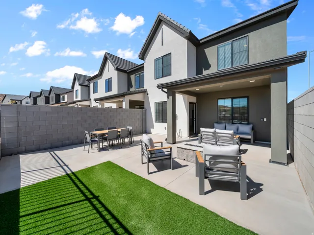 Private outdoor patio featuring a covered area, concrete hardscaping, artificial turf, and a built-in fire pit