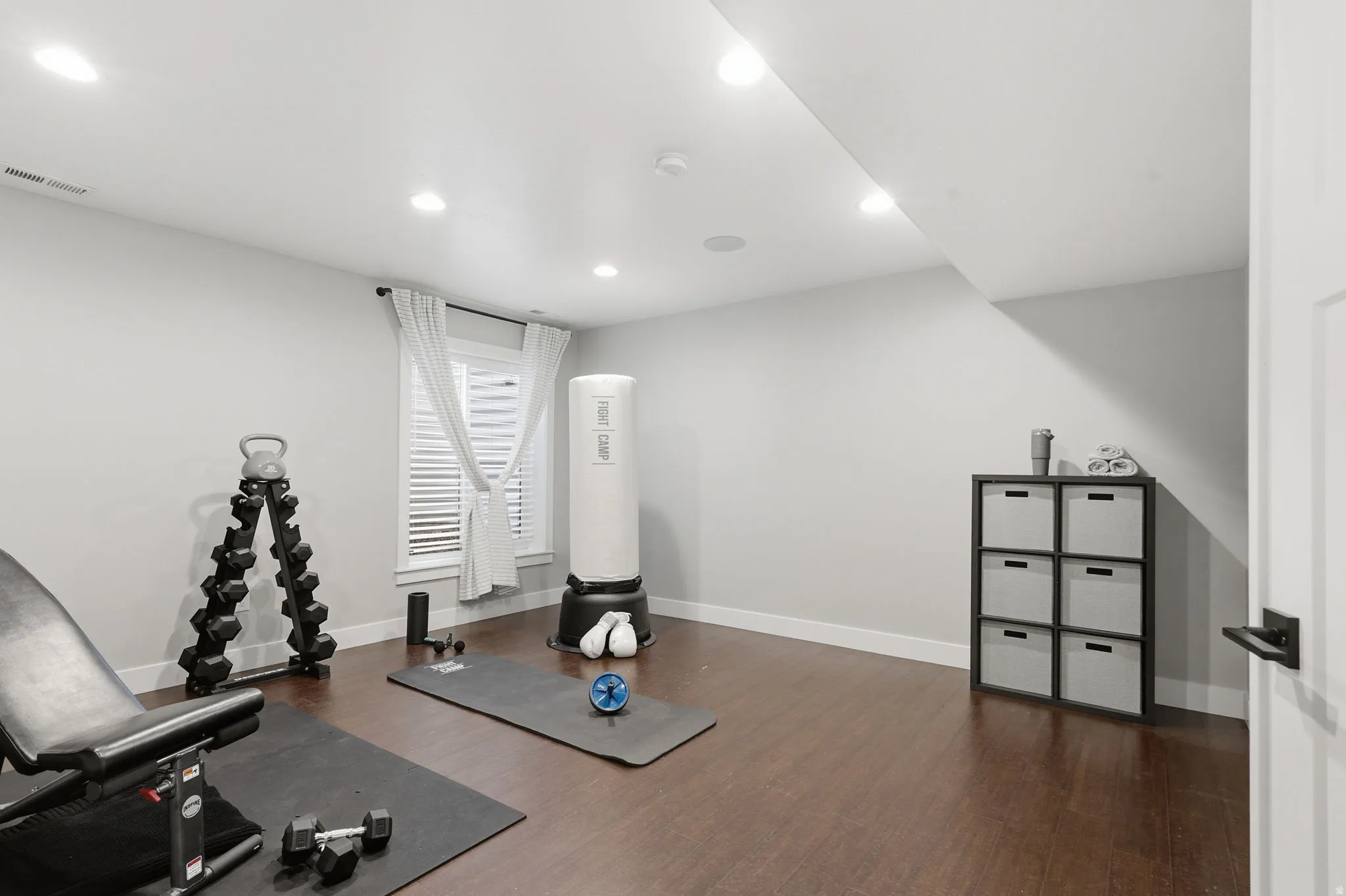 Workout room with dark wood-style floors and recessed lighting
