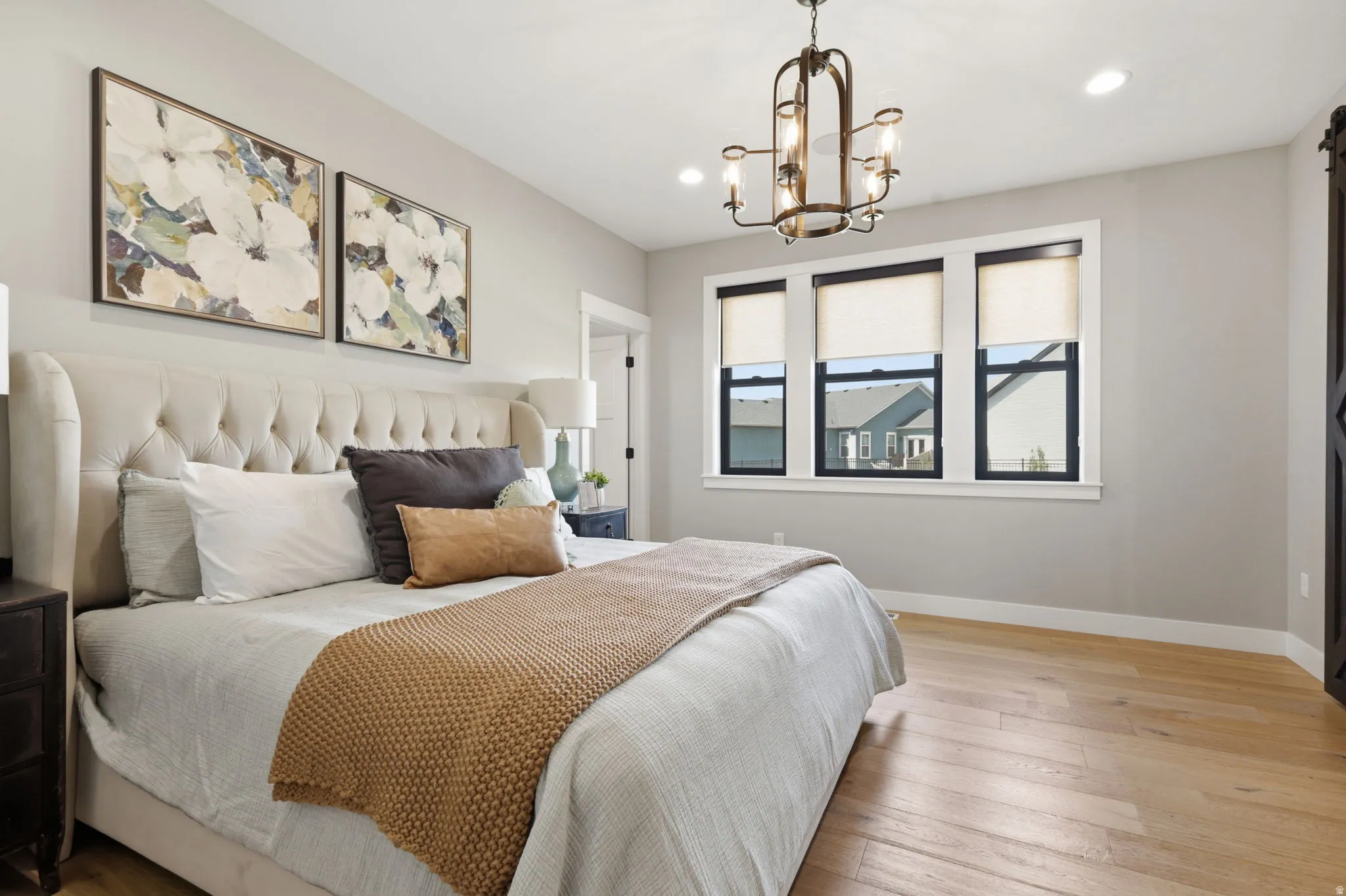 Bedroom featuring light wood-style floors, a chandelier, and a barn door