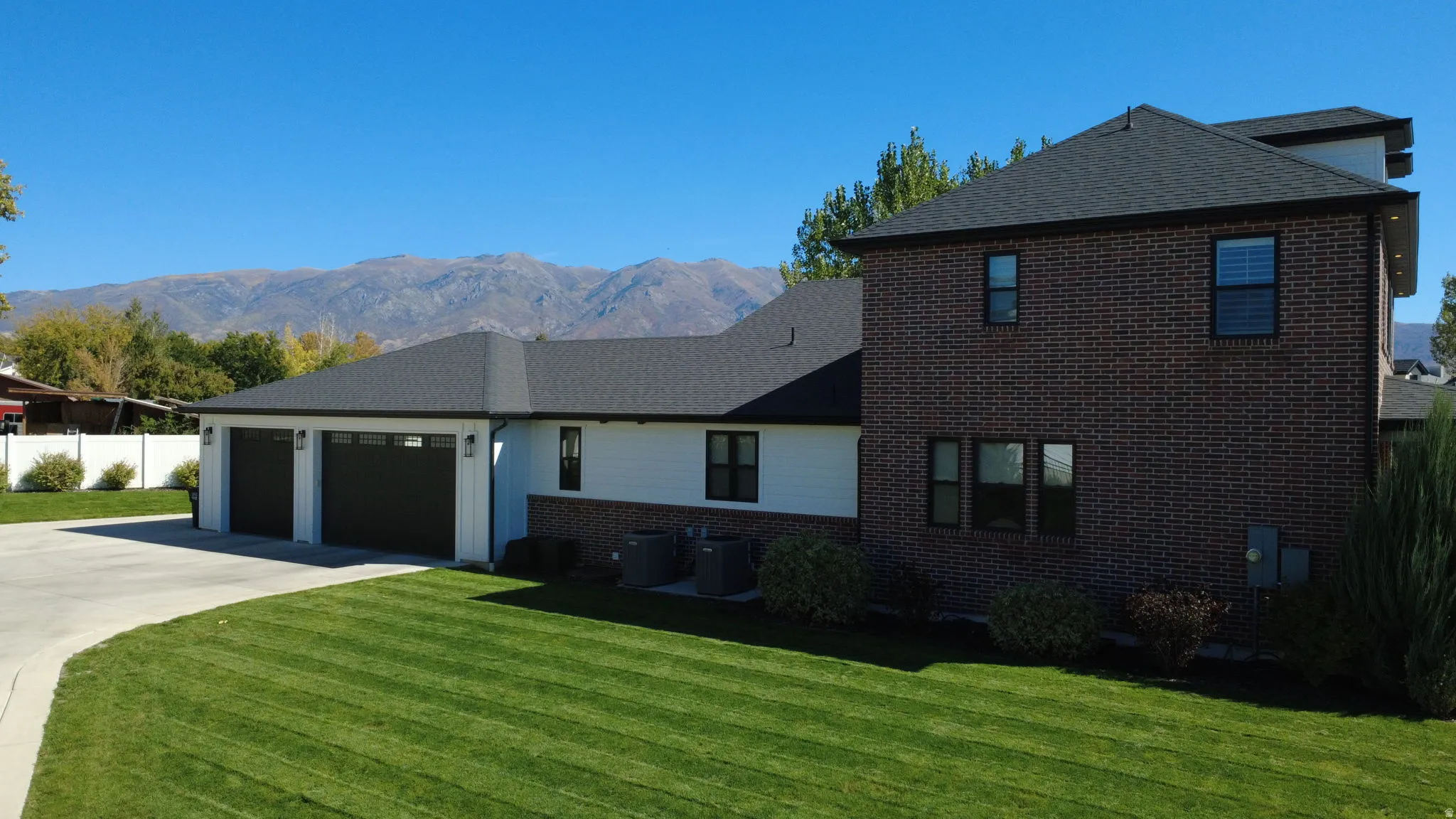View of front of home with brick siding, a garage, a mountain view, and concrete driveway