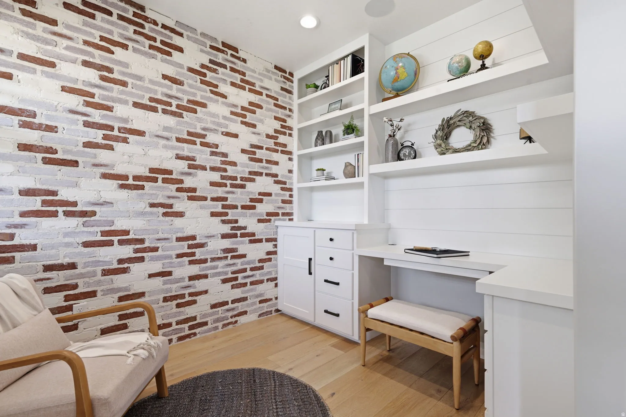 Sitting room with built in study area, light wood-type flooring, brick wall, and recessed lighting
