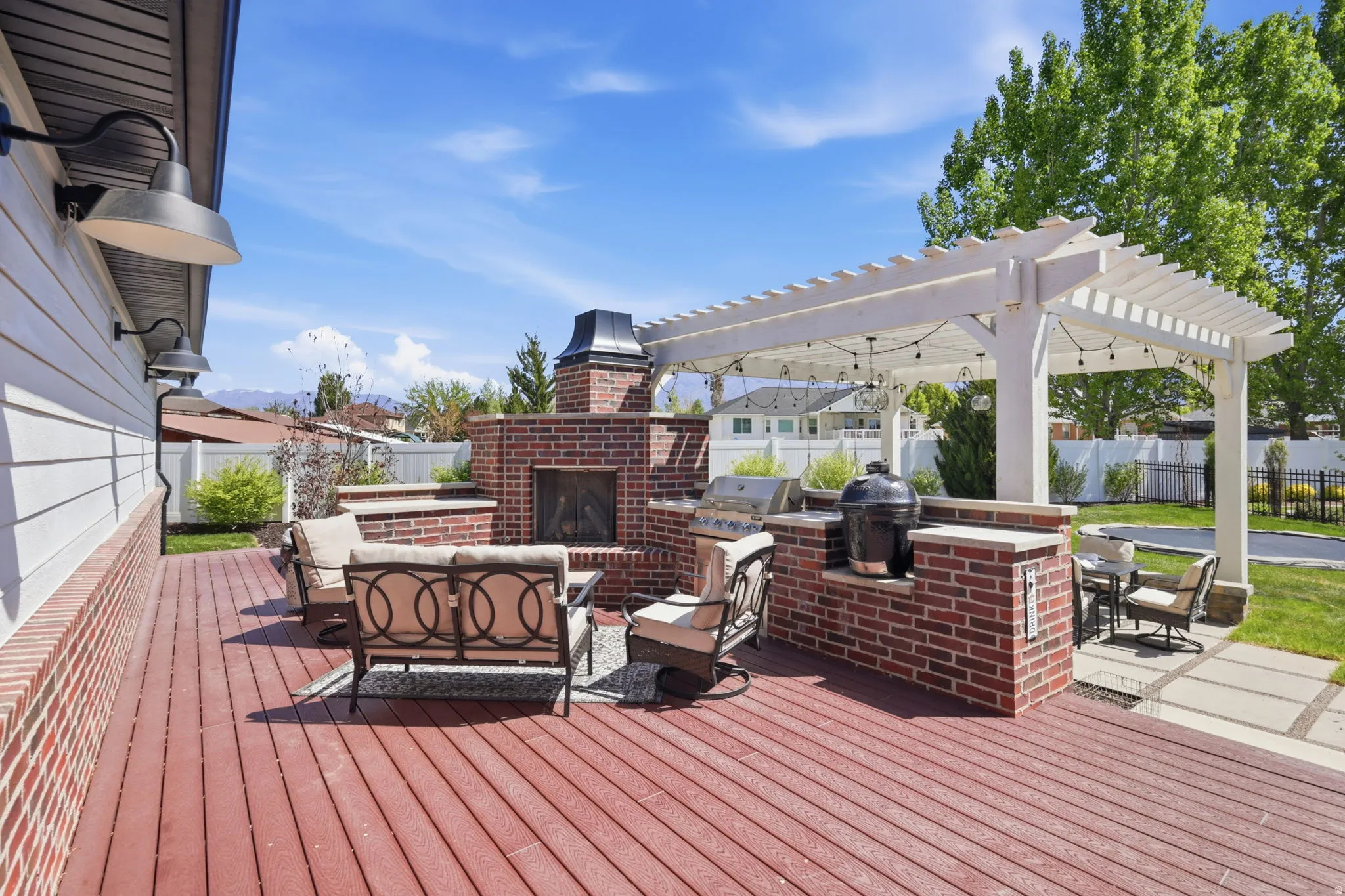 Wooden terrace featuring an outdoor kitchen, an outdoor brick fireplace, and outdoor lounge area