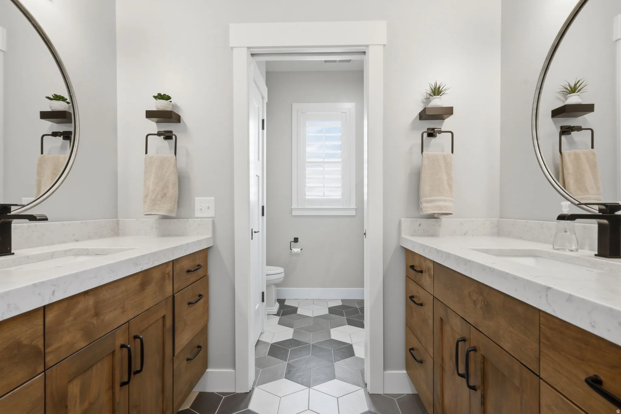 Full bath with two vanities and dark tile patterned flooring