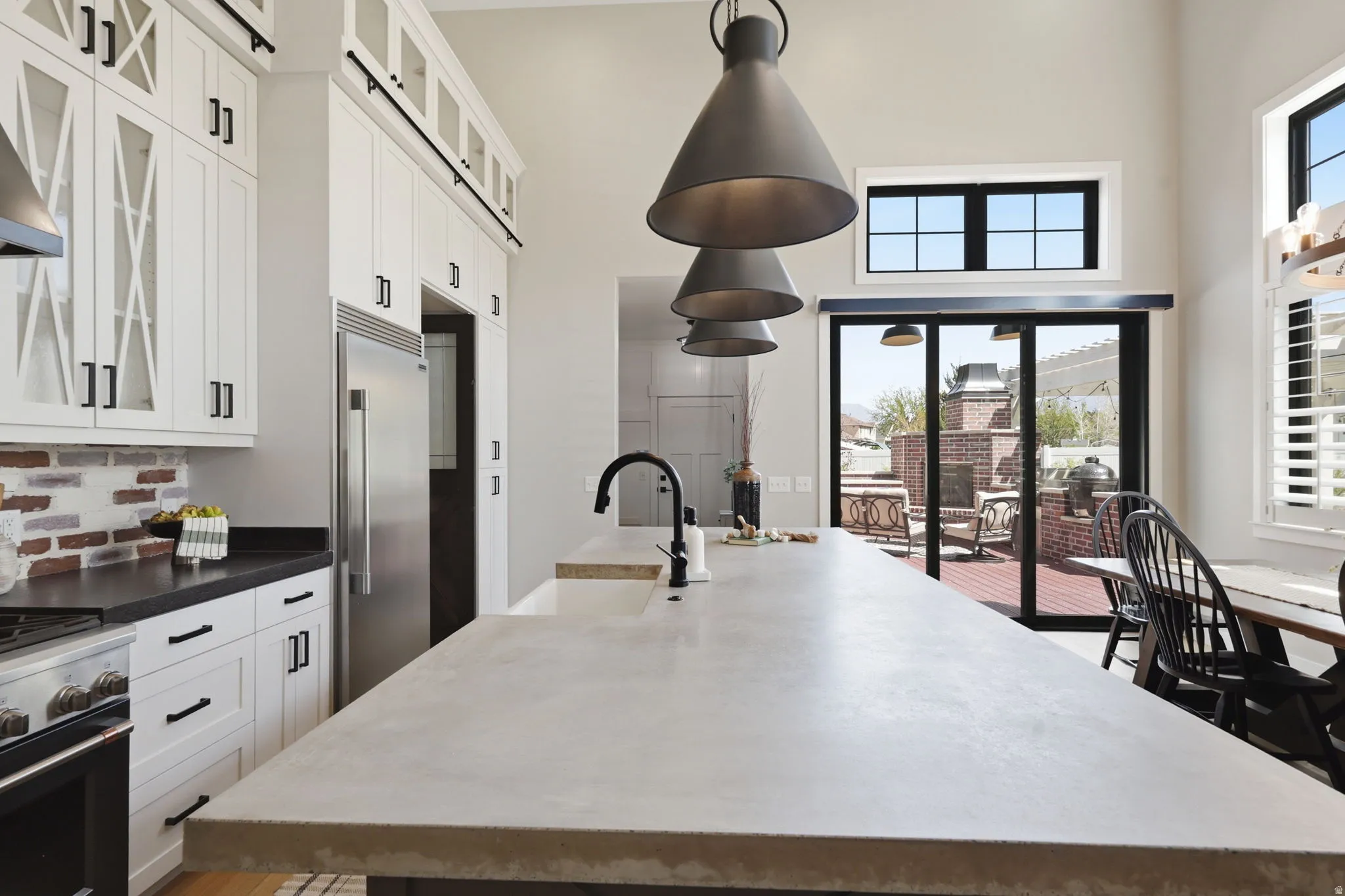 Kitchen with glass fronted cabinets, white cabinetry, premium appliances, a large island, and a high ceiling