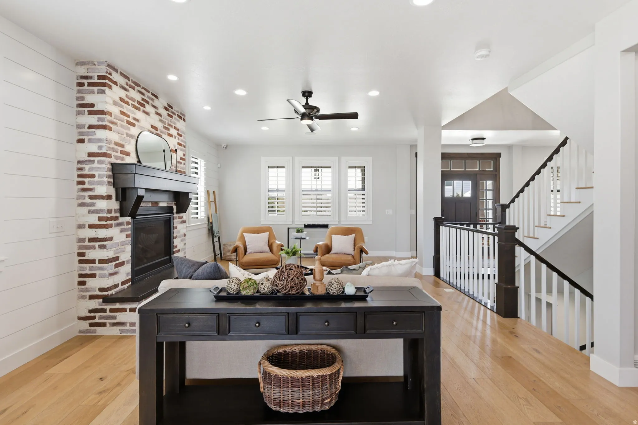 Living area with a brick fireplace, light wood finished floors, ceiling fan, and recessed lighting
