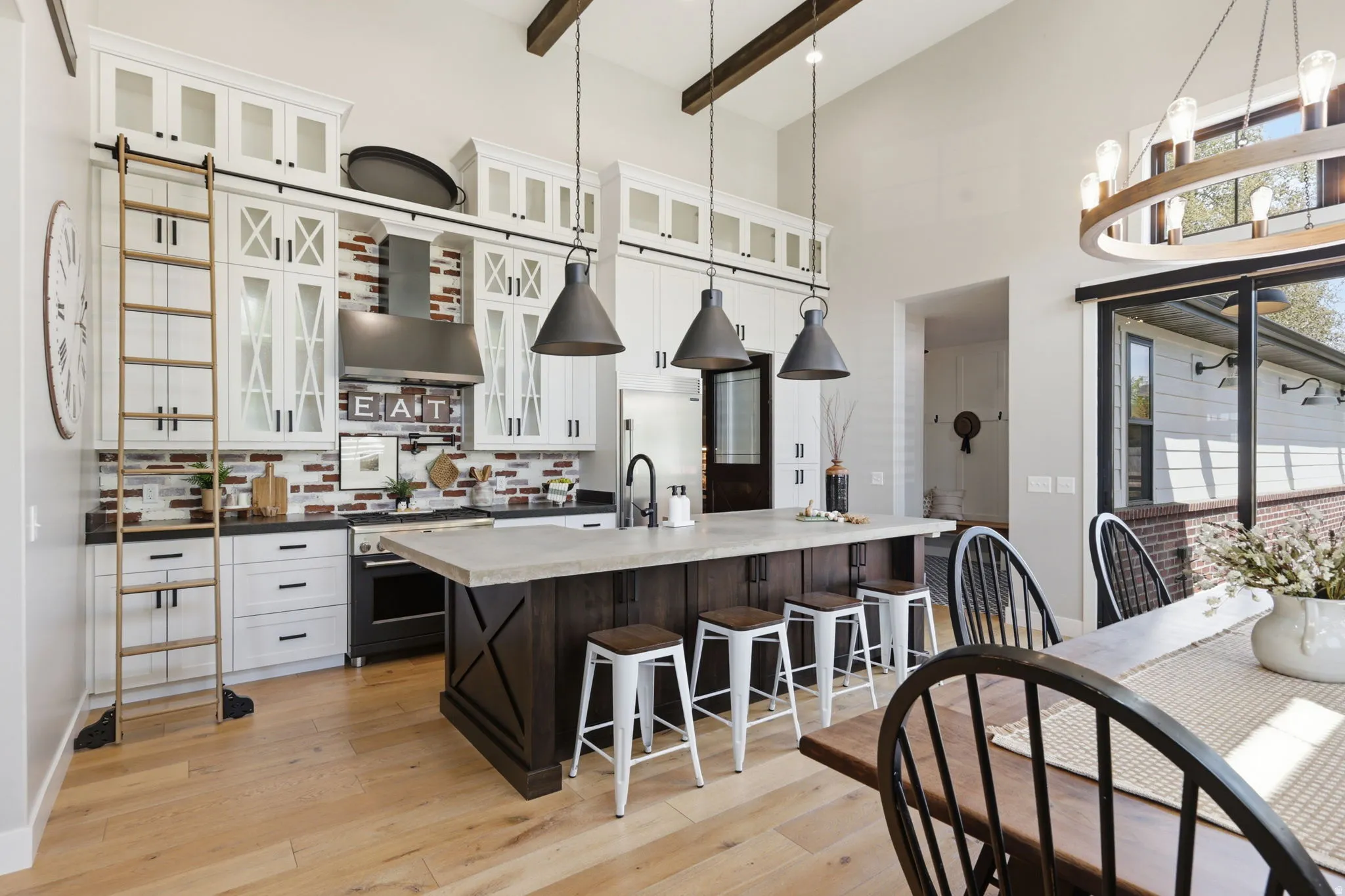 Kitchen featuring two tone cabinetry, a breakfast bar, light wood-type flooring, high end appliances, and glass fronted cabinets