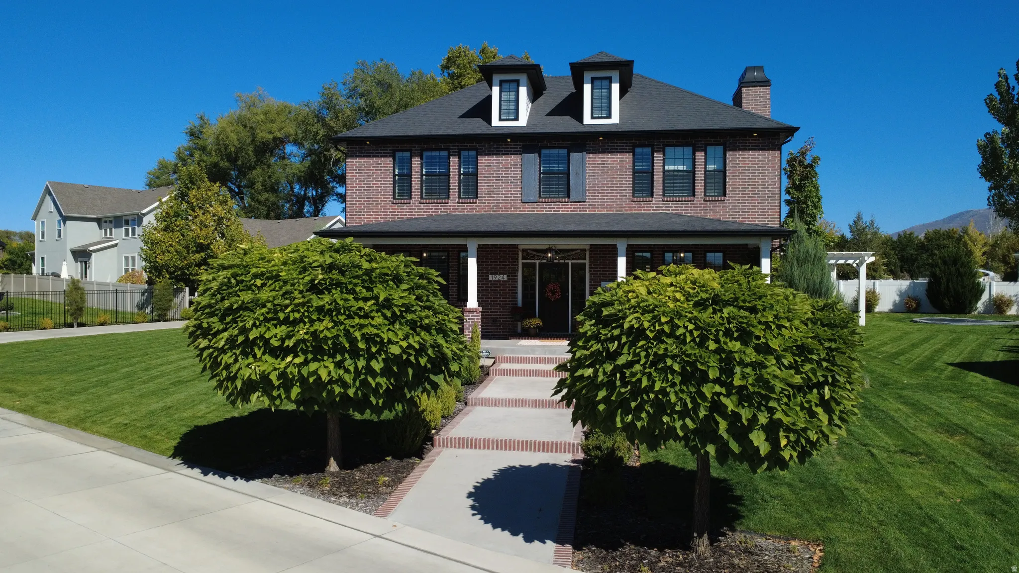 View of front of house with covered porch, brick siding, and a chimney