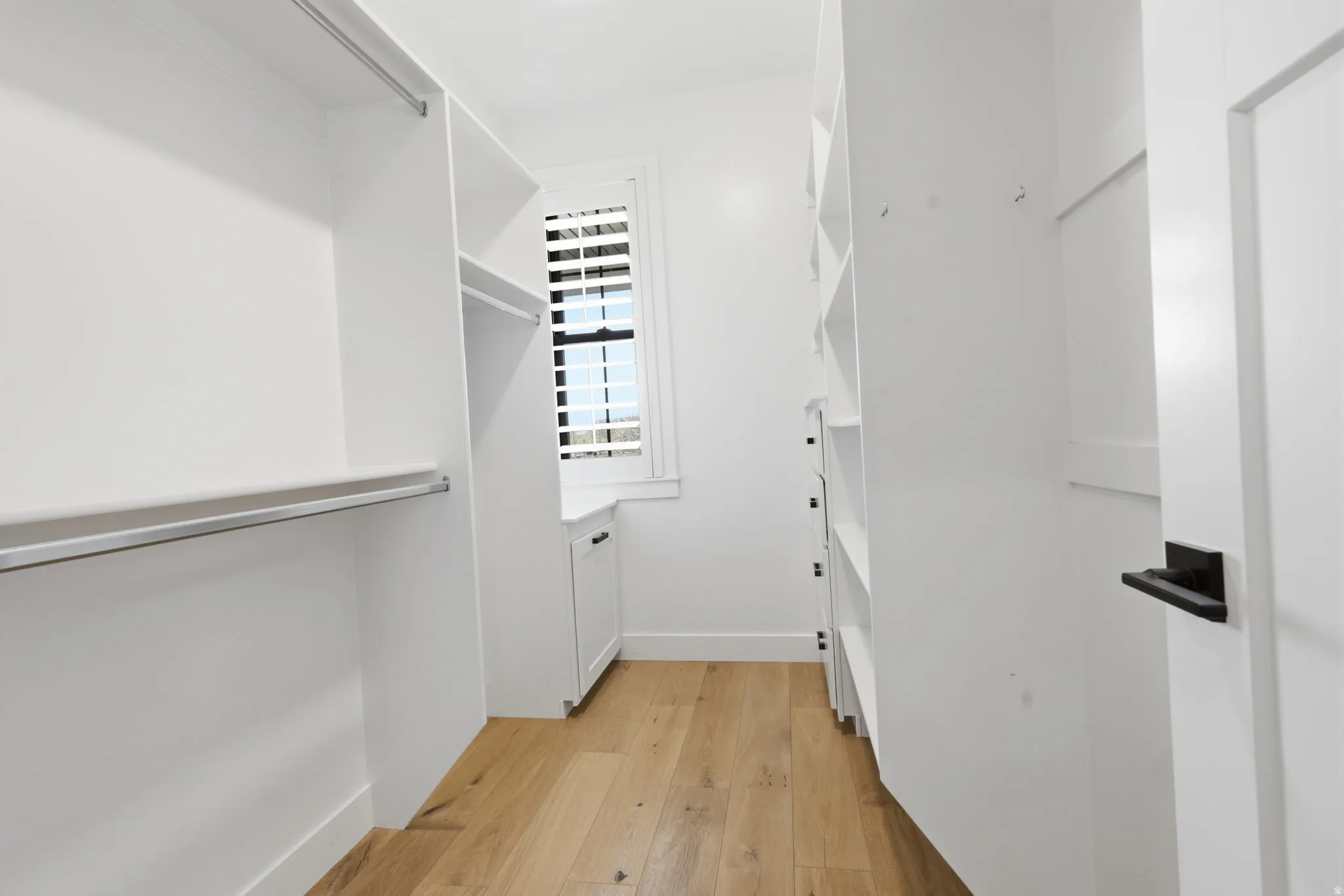 HIS walk in closet featuring light wood-style flooring