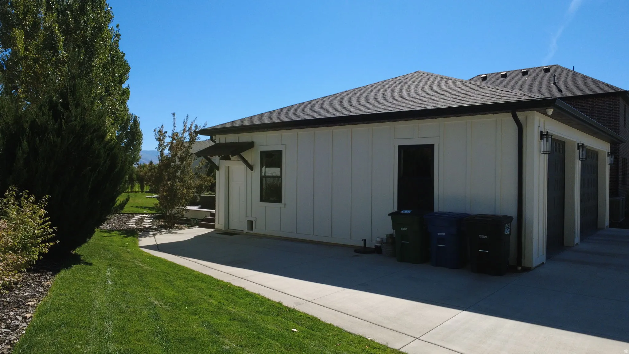 View of home's exterior with board and batten siding, a lawn, and a shingled roof