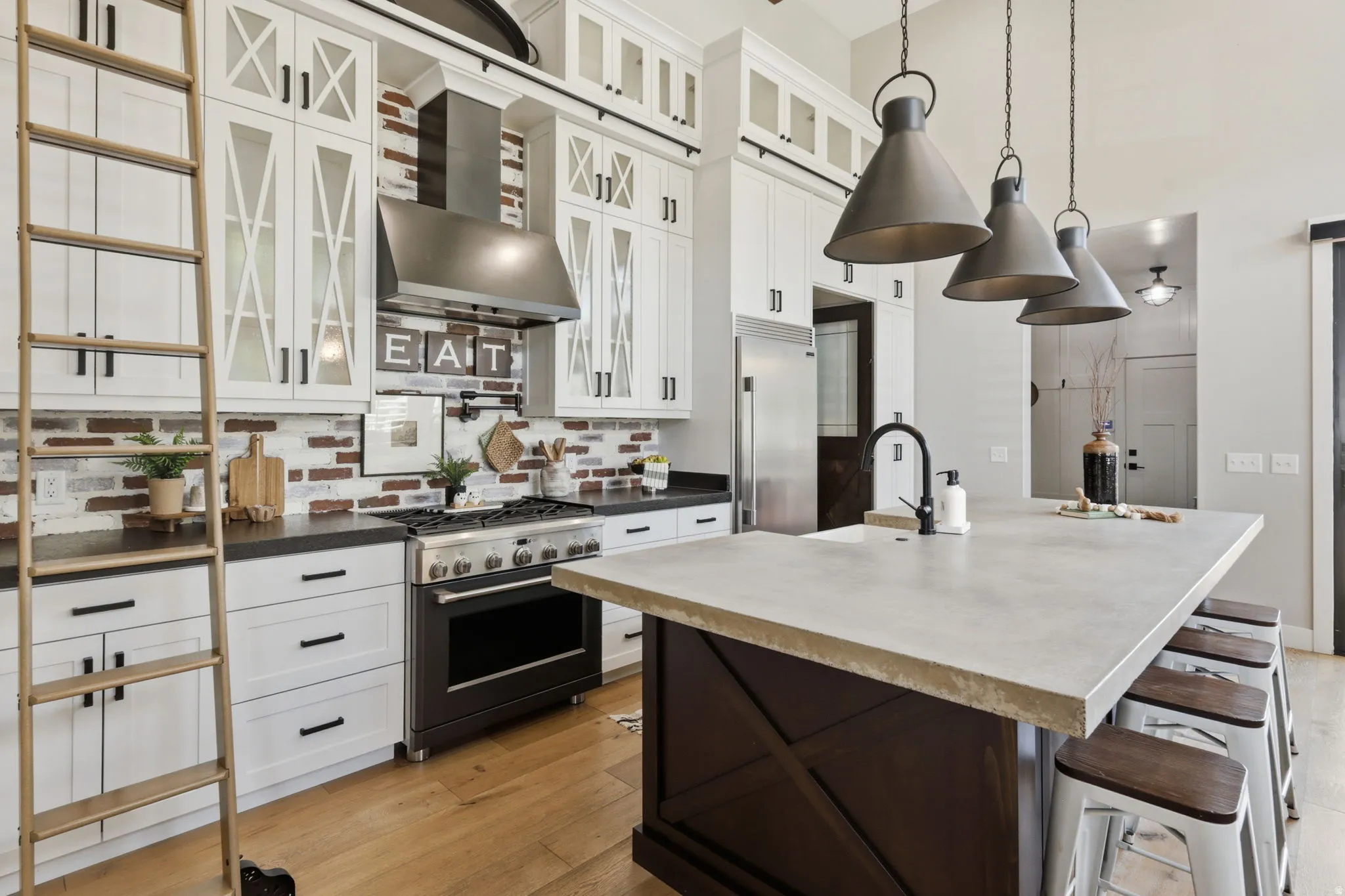 Kitchen featuring a breakfast bar area, light wood-style flooring, high end appliances, dual tone cabinetry, and decorative light fixtures
