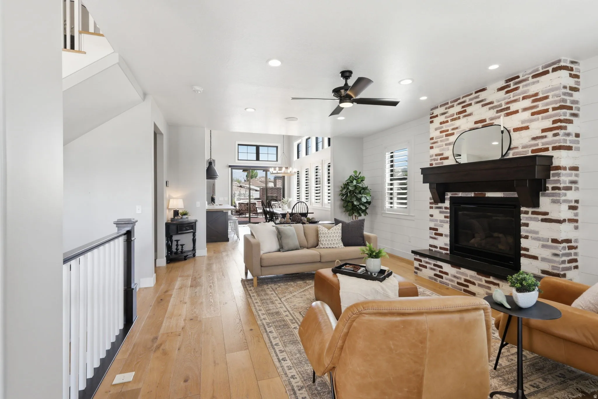 Living room featuring light wood-style floors, a brick fireplace, ceiling fan, and recessed lighting