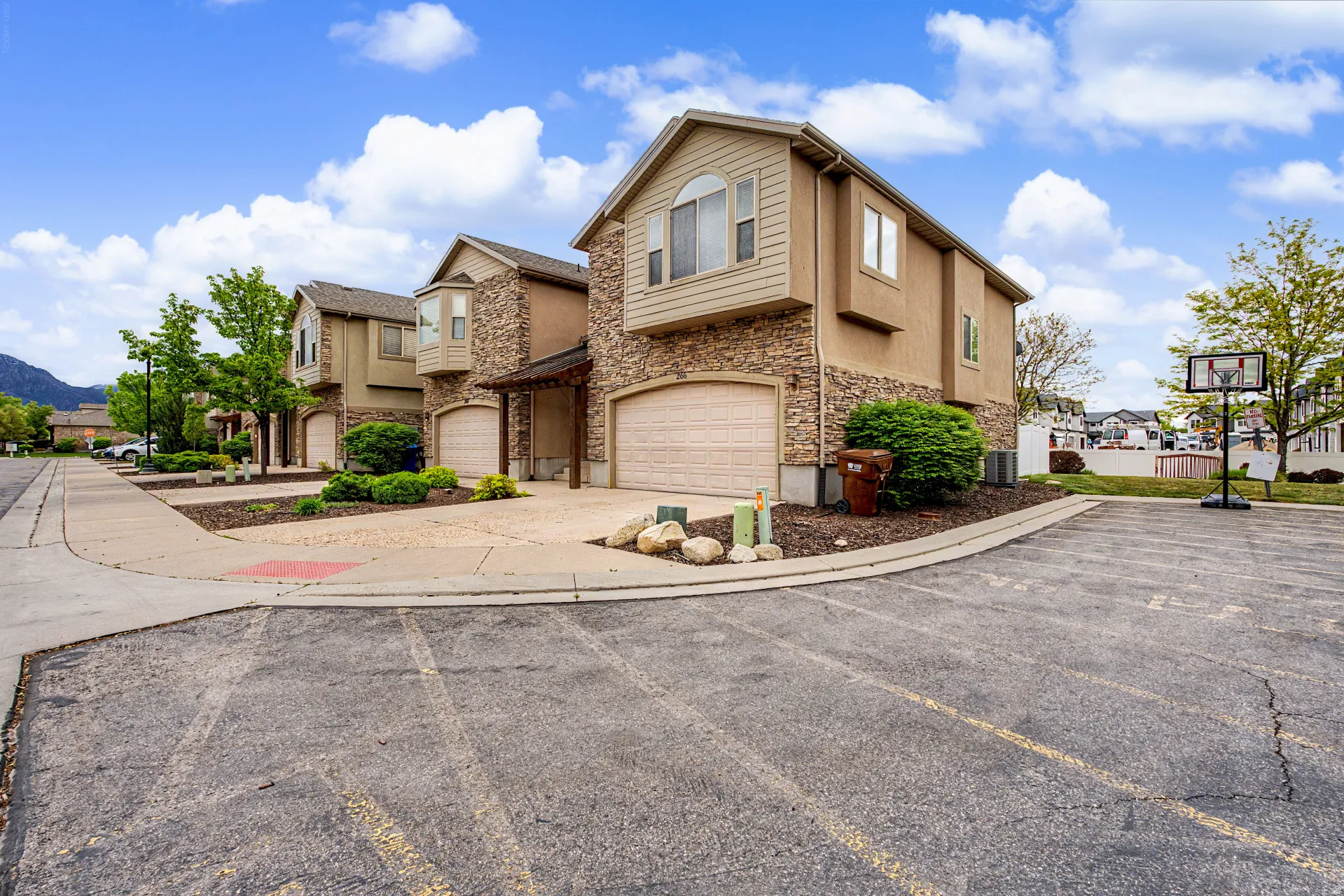 Traditional-style house with stone siding, an attached garage, stucco siding, concrete driveway, and a residential view